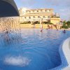 Una piscina con cascata e un edificio giallo sullo sfondo.
