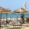 Una spiaggia con ombrelloni di paglia e lettini, vista mare.