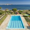 Piscina rettangolare vicino al mare, giardino intorno.
