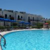 Una piscina con ombrelloni blu, palme e un paesaggio naturale sullo sfondo.