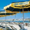 Ombrelloni gialli e blu su una spiaggia affollata, cielo limpido.