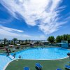 Piscina all'aperto, cielo blu con nuvole bianche.