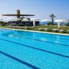Una piscina luminosa con vista su ombrelloni bianchi e mare in lontananza.