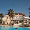 Piscina con palme e edificio sullo sfondo in una giornata soleggiata.