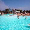 Persone giocano in una piscina con attrazioni acquatiche.