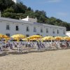 Ombrelloni gialli su spiaggia davanti a edificio bianco.