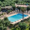 Piscina circondata da ombrelloni e alberi.<br>